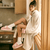 Woman in a cream robe sitting on a kitchen counter wearing pink Hello Kitty terry slippers with white bow and holding a pink mug