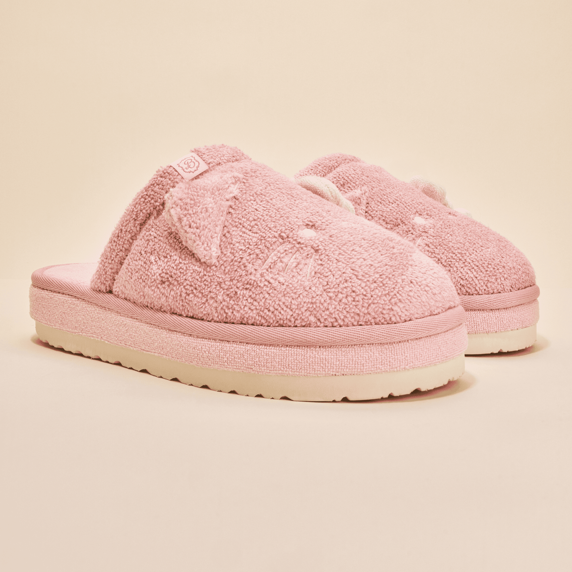 Front three-quarter of pink Hello Kitty terry slippers with 3D ears, embroidered face, and thick platform sole