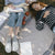 Person wearing cream suede Yankees loafers sitting with legs extended on a picnic blanket with notebook, apples, and earbuds nearby