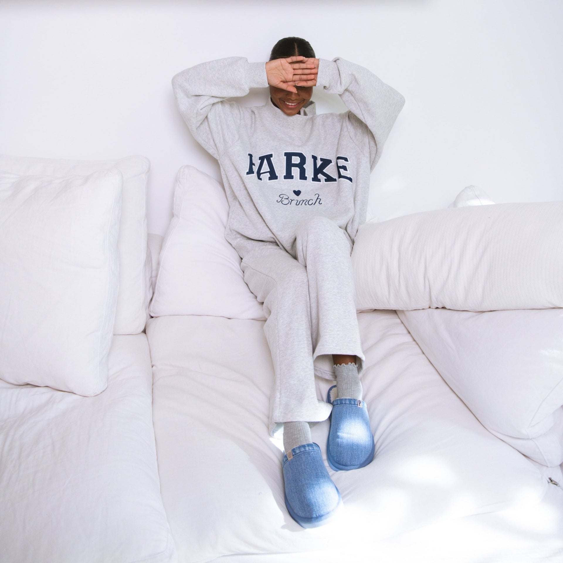 Front view of Parke fleece sweatpants in classic grey on model showing relaxed fit seated on cream couch