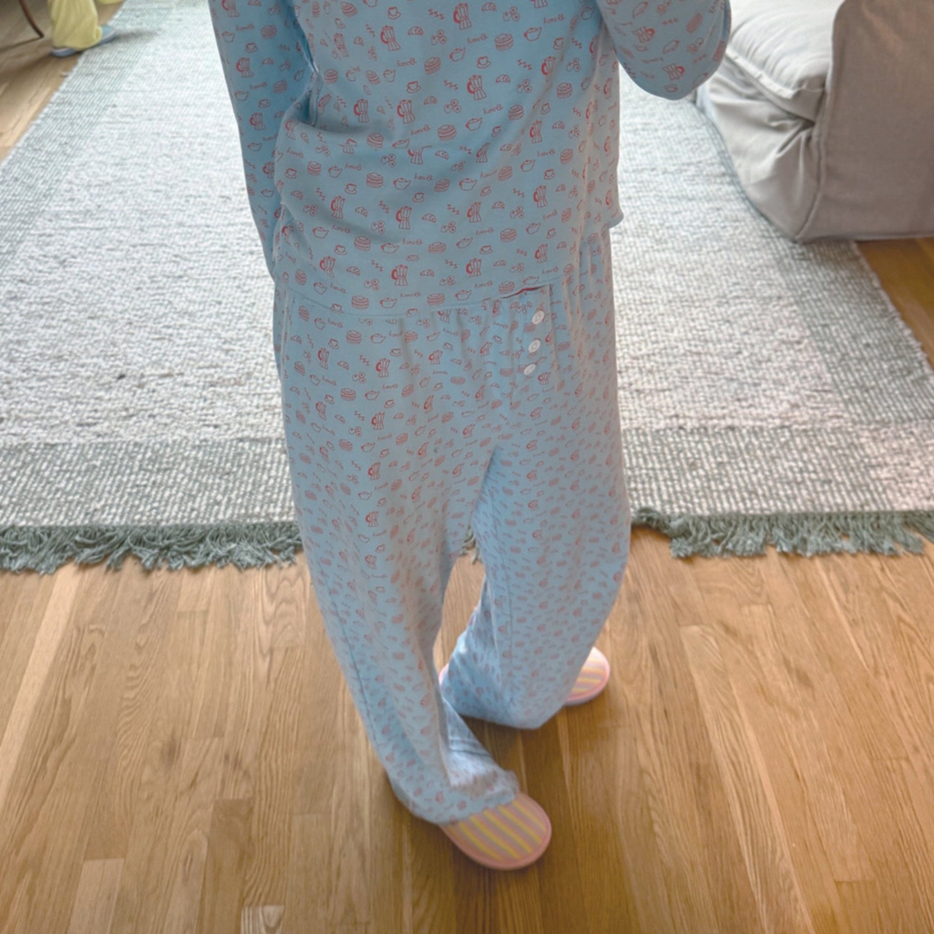 Front view of French Blue Cozyland pajama set with small pink print and relaxed wide-leg pants with button fly on hardwood floor
