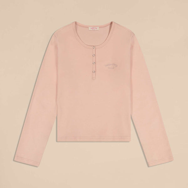 Flat-lay of pink long-sleeve pajama top showing snap-button placket and small Hello Kitty embroidery on left chest
