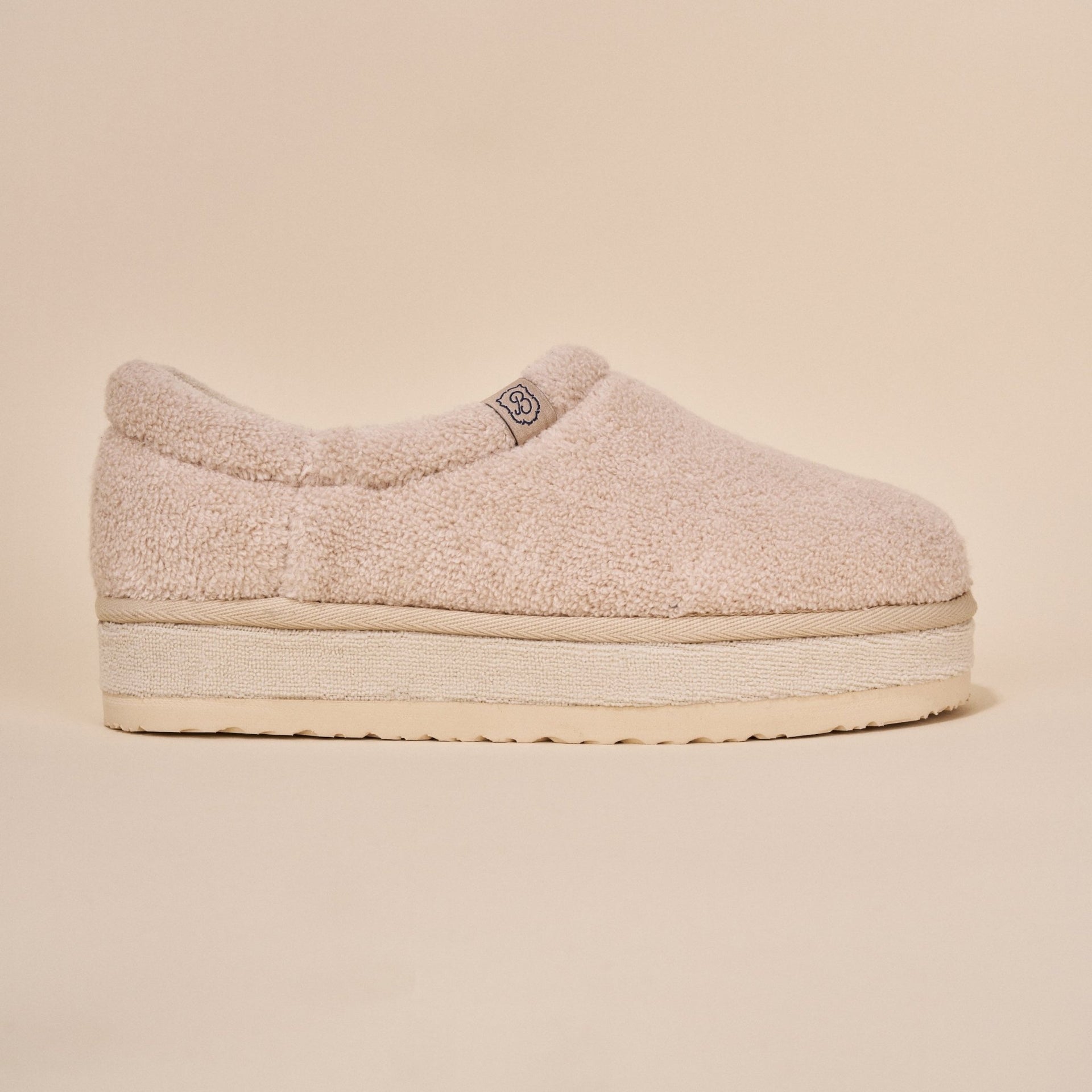 Side view of Puff XXL slipper in beige terry showing structured back and extra-thick platform sole on beige background