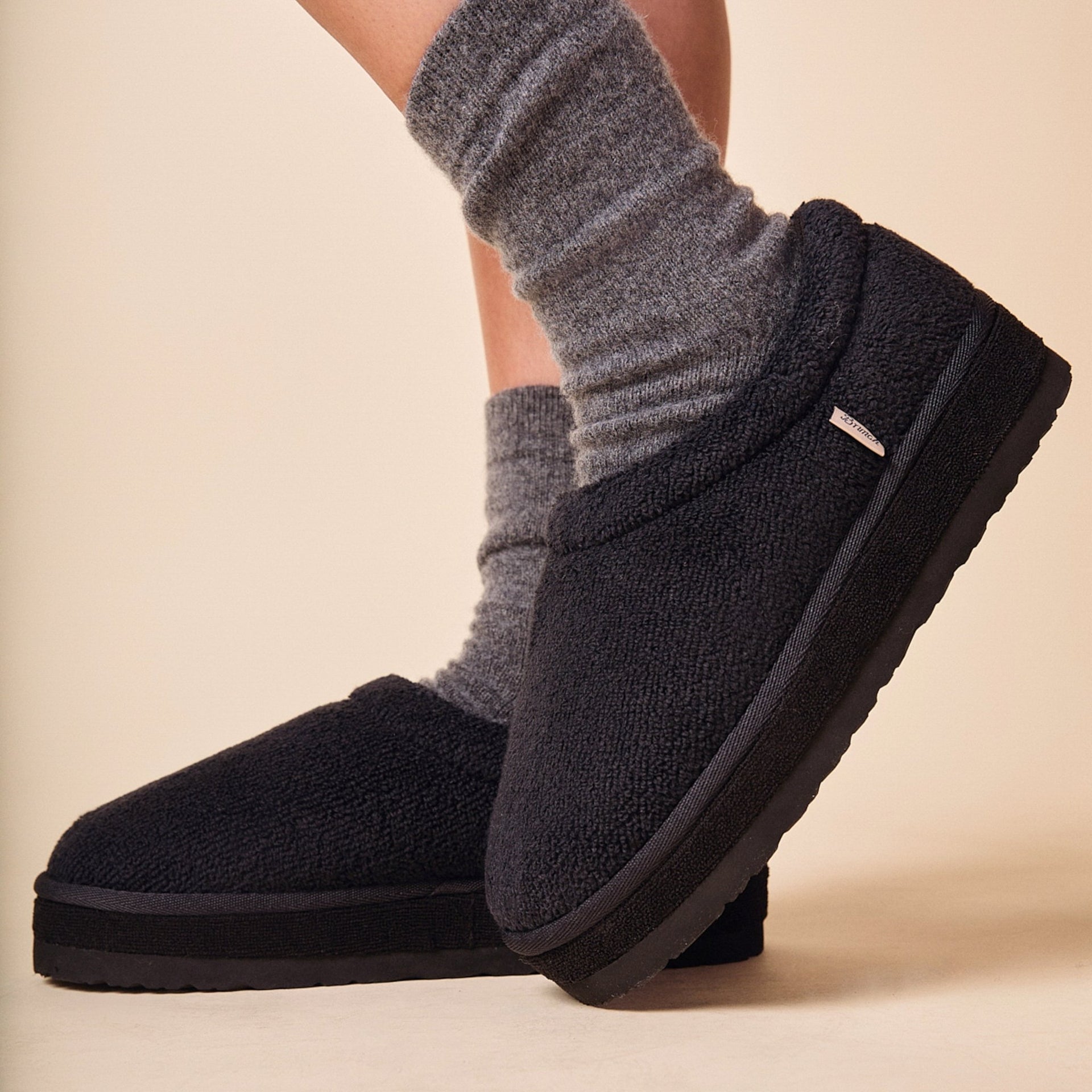 Side view of Puff XXL slipper in black terry showing extra-thick platform sole and structured back on a neutral background