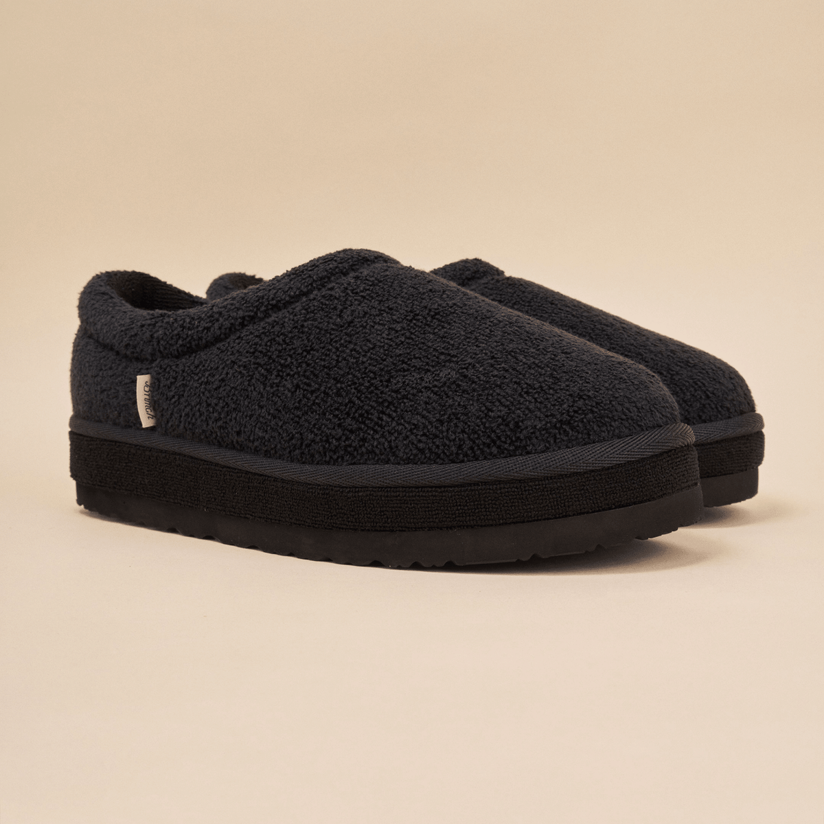 Front three-quarter view of Puff XXL slipper in black terry showcasing extra-thick platform outsole and textured terry upper on beige studio background
