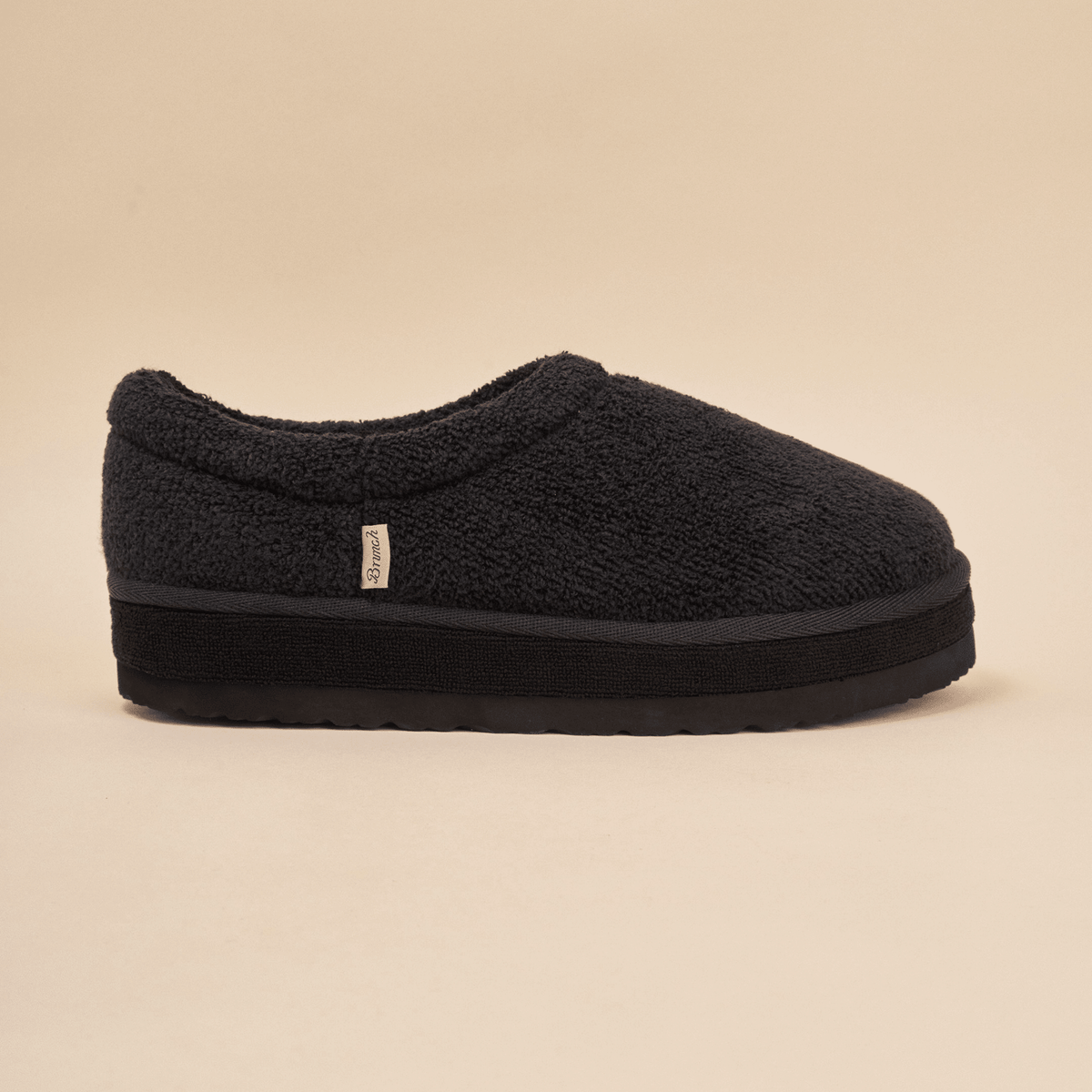Side view of Puff XXL slipper in black terry showcasing extra thick platform sole and Brunch tag on beige background