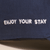 Close-up of Retro Brunch Cap showing white embroidered ENJOY YOUR STAY slogan on navy cotton fabric