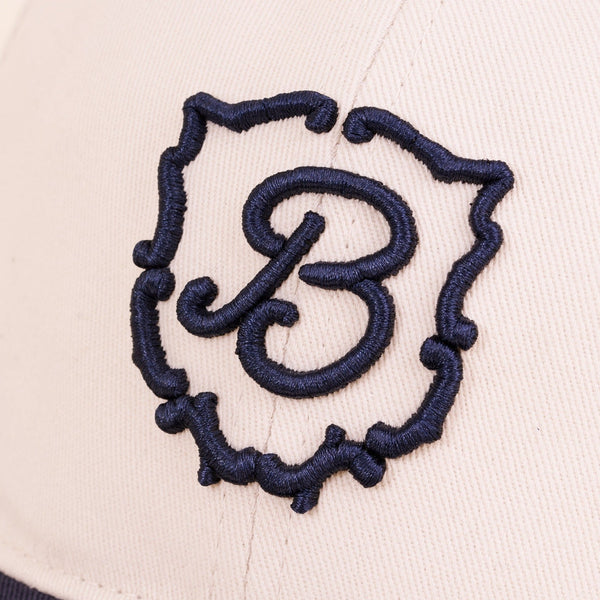 Close-up of Retro Crest cap front panel showcasing navy embroidered B crest on cream cotton fabric