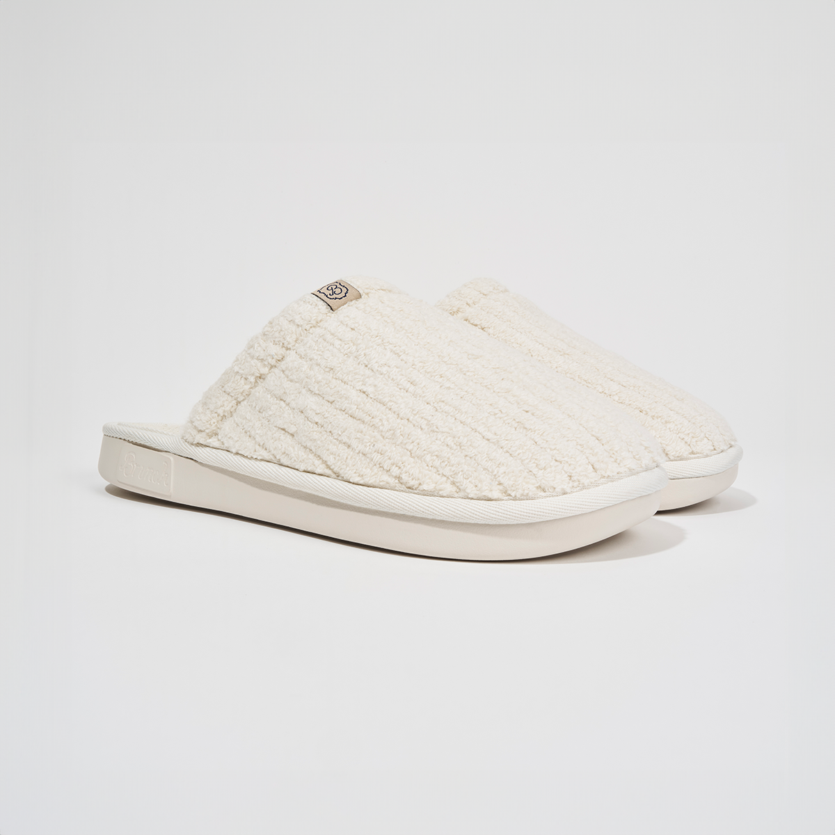 Angled side view of The Essential slipper in Panna ribbed terry showing plush ribbed upper and EVA outsole on white background