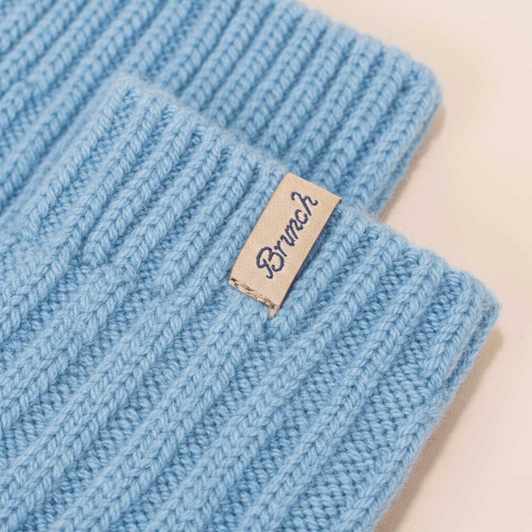 Close-up of powder blue cashmere-wool sock cuff showcasing ribbed knit texture and Brunch cloth label on pale beige background