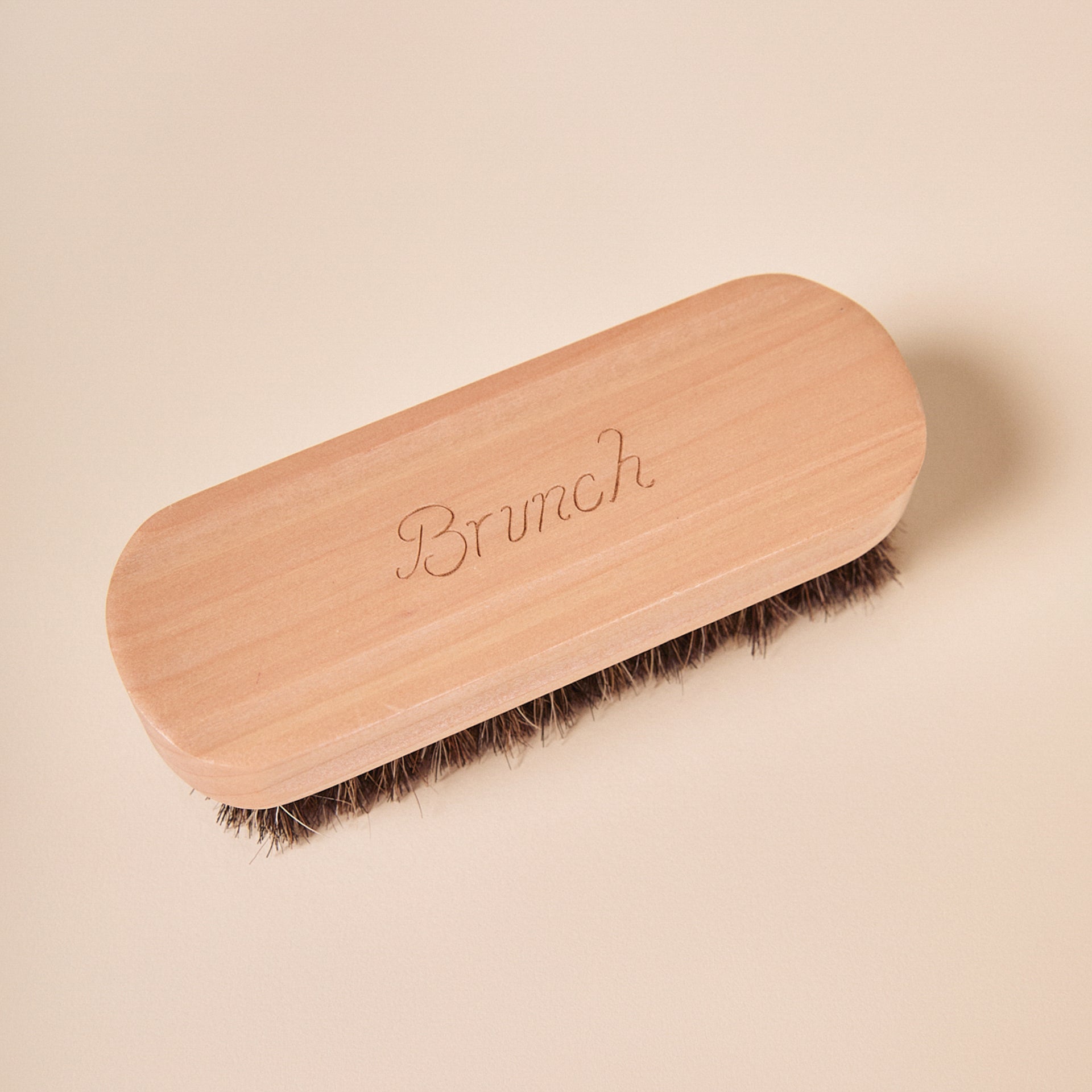 Wooden shoe brush with engraved script 'Brunch' and dark bristles