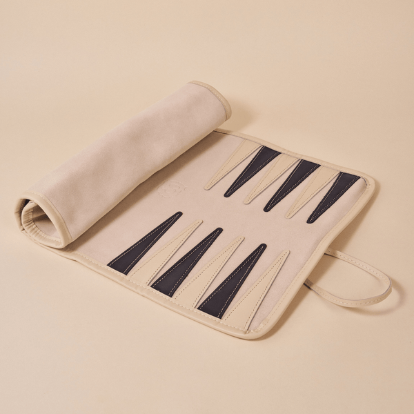 Angled top-down view of backgammon set opened to show beige suede interior with dark leather points on beige background