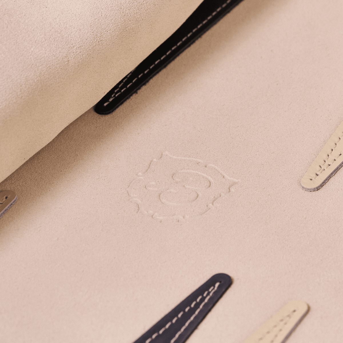 Close-up of Travel Backgammon Set interior showing beige suede texture, embossed Brunch logo, and stitched leather tabs